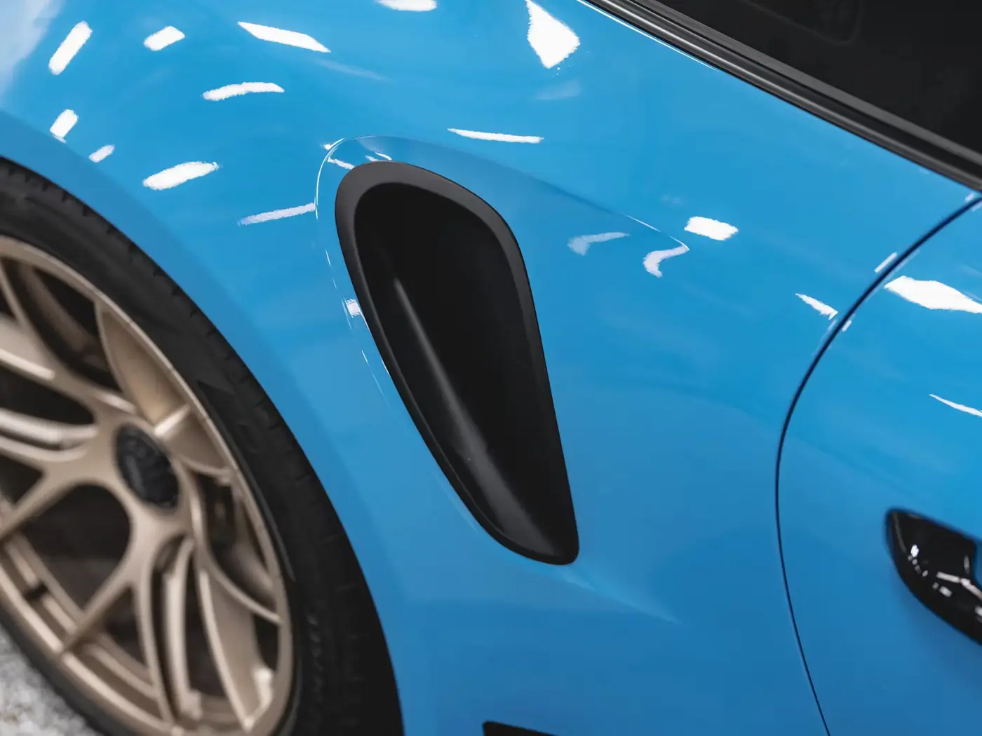 Parlak mavi Color PPF uygulanmış spor otomobilin çamurluk ve jant detayı